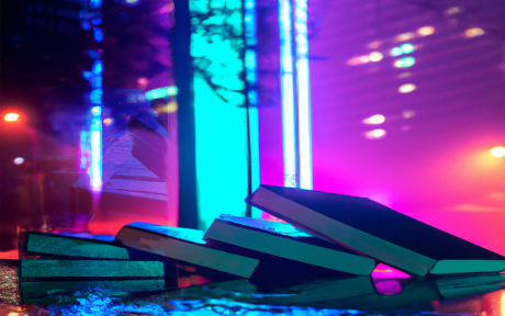 Stack of tech books in front of window lit by neon colors - image created by Amber Ankerholz