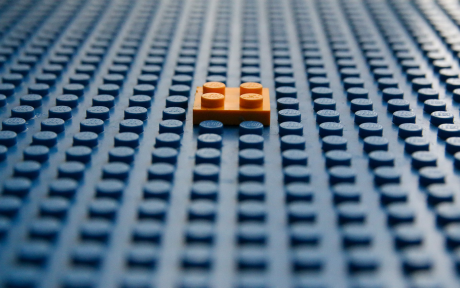 Lego Blue Lego board with one orange lego in the middle - Photo by Glen Carrie on Unsplash