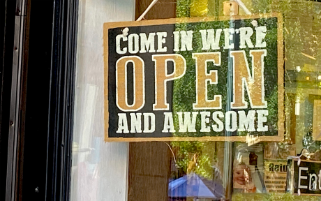 Yellow and black sign in business window saying Come in, we're open and awesome - Photo by Amber Ankerholz
